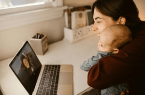 This image depicts a smiling mother and child video calling with her husband on a laptop, depicting another way how telecom investment benefits the military. 